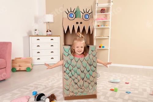 Preview: Cute little girl playing with cardboard dragon at home