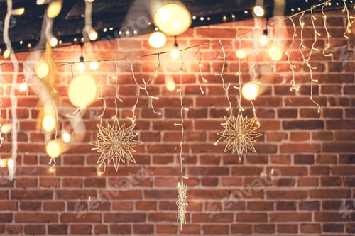 Preview: Lights garlands hanging from brick wall at evening, Christmas house decoration.