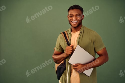 Preview: Distance learning. Glad african american guy with backpack and wireless laptop posing over green bac