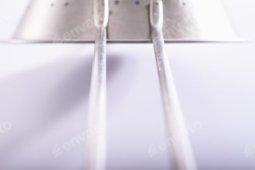 Preview: Detail, with unfocused background, of a metallic steel kitchen accessory in white light background.