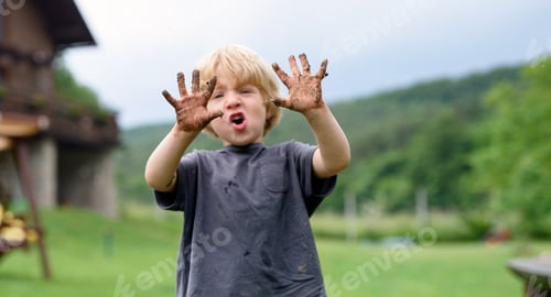 Preview: Small boy with dirty hands standing in vegetable garden, sustainable lifestyle