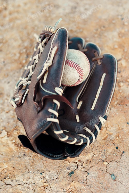 Preview: Shot of a baseball mitt and ball lying on the pitch during the day