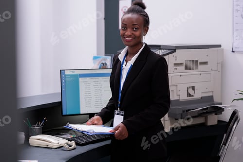 Preview: Portrait of receptionist in black suit standing at hospital counter desk looking at checkup visit