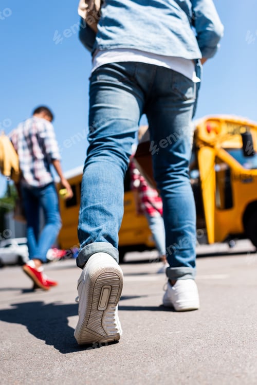 Preview: cropped shot of schoolboy walking at school bus with classmates