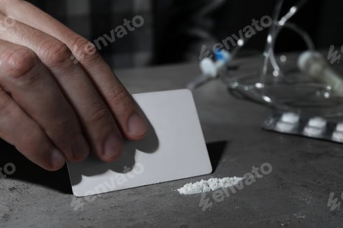 Preview: Addicted man preparing drugs for consumption at grey table, closeup