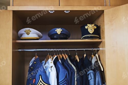 Preview: Not every hero wears a cape. Shot of various military jackets and hats hanging in a closet.