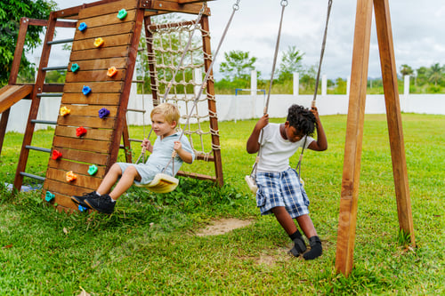 Preview: Two children enjoy a day outdoors, swinging and climbing in a colorful playground setting