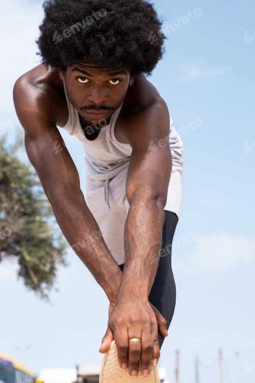 Preview: Confident sportsman stretching body against sky