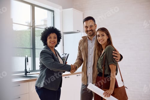 Preview: Happy couple and real estate agent shaking hands and looking at camera.