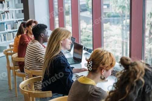Preview: College students studying together in a brightly lit library with a large window