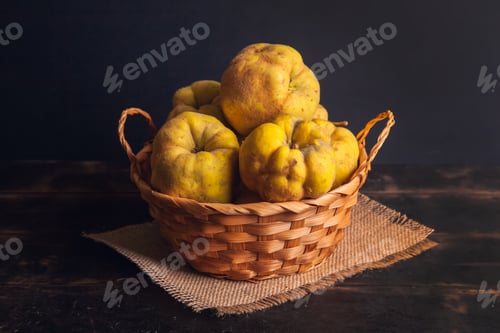 Preview: Natural quince fruit with defects in a basket on a jute napkin and a dark wooden background