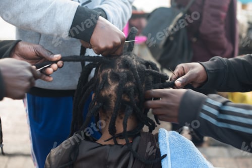 Preview: Close up shot of group of people tending to dreadlocks hair