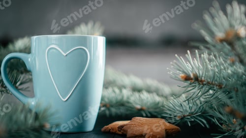 Preview: Blurred blue cup with heart with Christmas tree branches and gingerbread cookies, copy space.