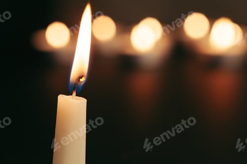 Preview: A single burning candle isolated with black background