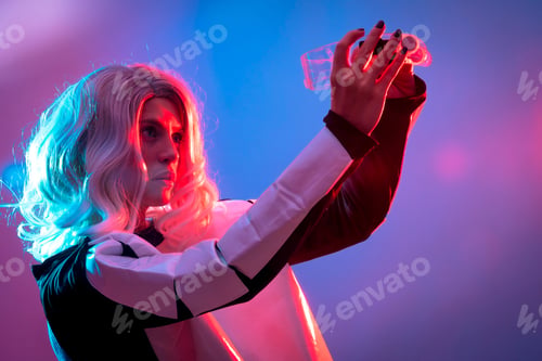 Preview: Beautiful woman looking at the futuristic glasses on a dark background, future and virtual reality