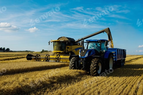 Preview: Combine harvester and tractor harvesting a crop in a field in summer.