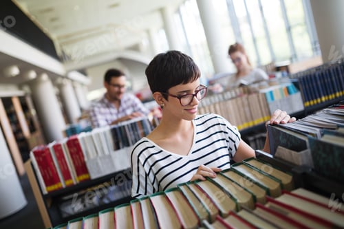 Preview: Portrait of a pretty smiling girl reading book in library