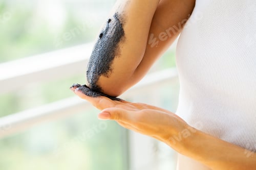 Preview: Woman cleans skin of the body with coffee scrub in bathroom.