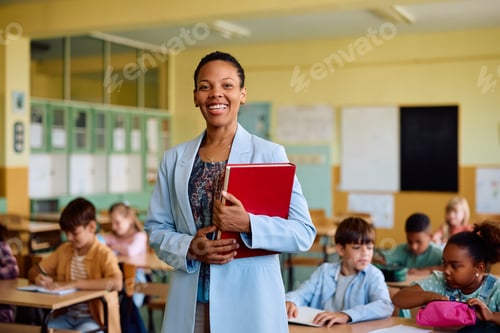 Visualização: Professora negra feliz durante uma aula na escola primária olhando para a câmera.