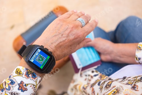 Preview: Woman with luggage, wearing wristwatch with digital certificate of vaccination against Covid-19