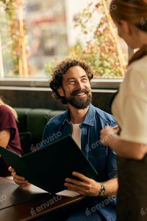 Preview: Smiling Man Interacting with Waitress While Holding a Menu in a Cafe