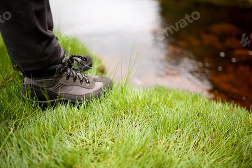 Preview: side view hiker standing in boots next to water