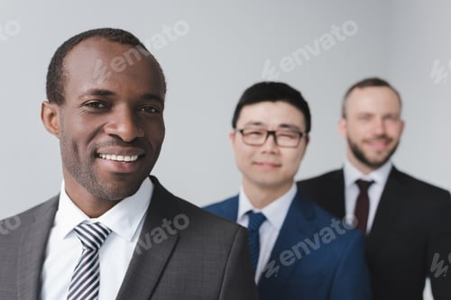 Preview: Businessmen Smiling in Suits in Front of Wall