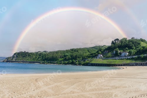 Preview: Getaria beach in Gipuzkoa (Basque Country, Spain) with cloudy sky and a rainbow on the horizon