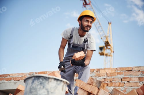 Preview: Blue sky and crane is behind. Handsome Indian man is on the construction site