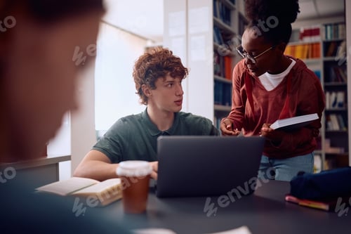 Preview: College students cooperating while studying in library.
