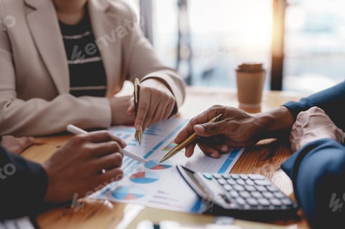 Preview: Business People Analyze Charts with Pens at Desk