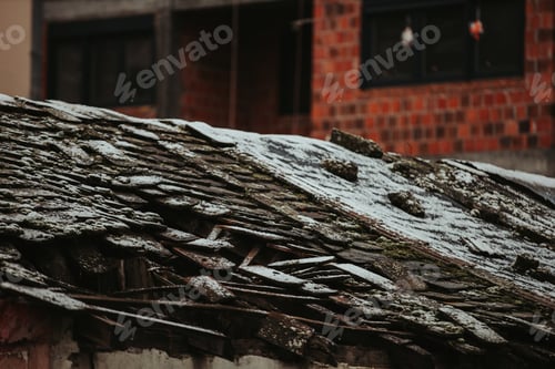Preview: Shot of an old broken roof covered in snow on the blurred background of the building with red stones