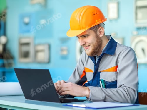 Preview: young happy engineer working at laptop in control room