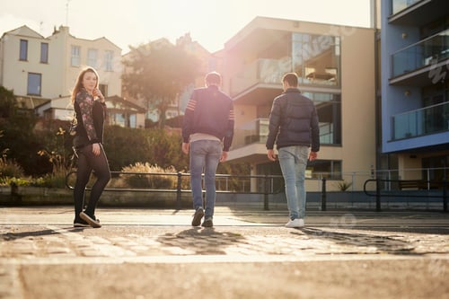 Preview: Three friends walking outdoors, young woman looking over shoulder, Bristol, UK