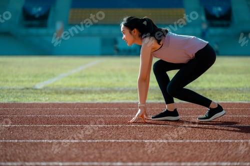 Preview: Young Asian athlete preparing for a race on a running track