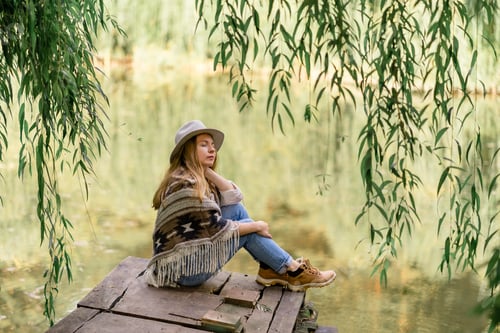 Preview: young beautiful girl sitting on the shore of the lake among the jungle