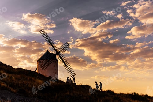 Preview: People walking around an ancient windmill in a hill during sunset
