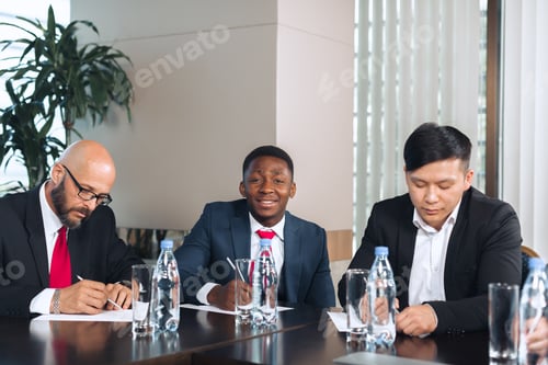 Preview: Business meeting featuring diverse professionals discussing strategies and signing documents