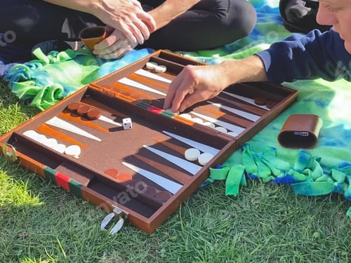 Preview: Playing backgammon together on the grass at the park while having a picnic.