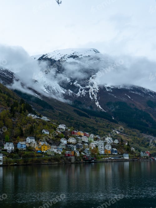 Preview: the beautiful fjord view of town on a cloudy day, with snow - capped mountains