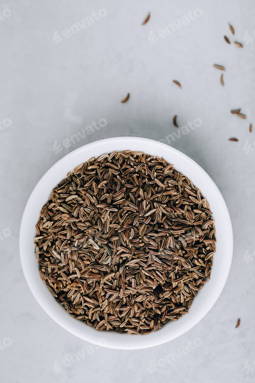 Preview: Cumin seeds or caraway in white bowl on gray stone background