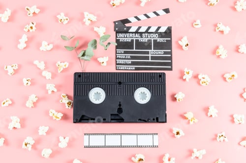Preview: One retro video cassette, paper movie clapperboard, film strip and sprinkled popcorn