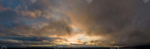 Preview: Dramatic Sunset Over Cloudy Sky With City Silhouette at Dusk in BC Canada