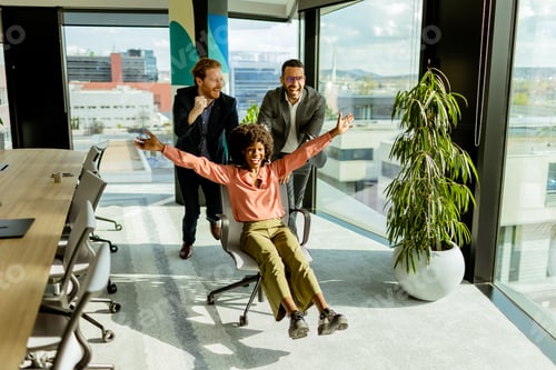 Preview: Jubilant Office Celebration Captures Colleagues Spontaneous Chair Race in Sunlit Room