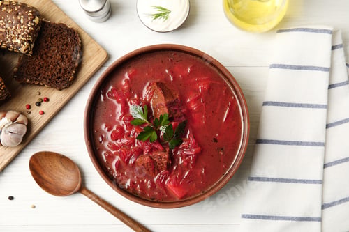Preview: Stylish brown clay bowl with Ukrainian borsch served on white wooden table, flat lay