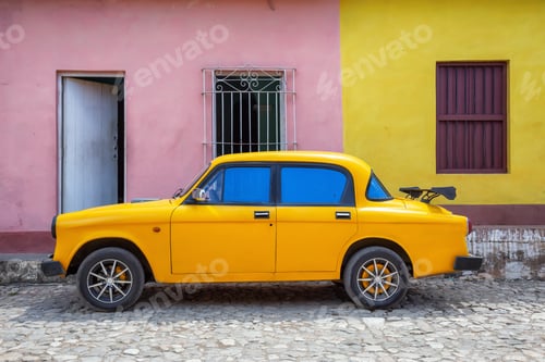 Preview: Old Yellow Car with colorful buildings in the background in a small Cuban Town