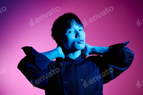 Preview: Stylish young Asian man poses confidently against a vibrant backdrop in a modern setting
