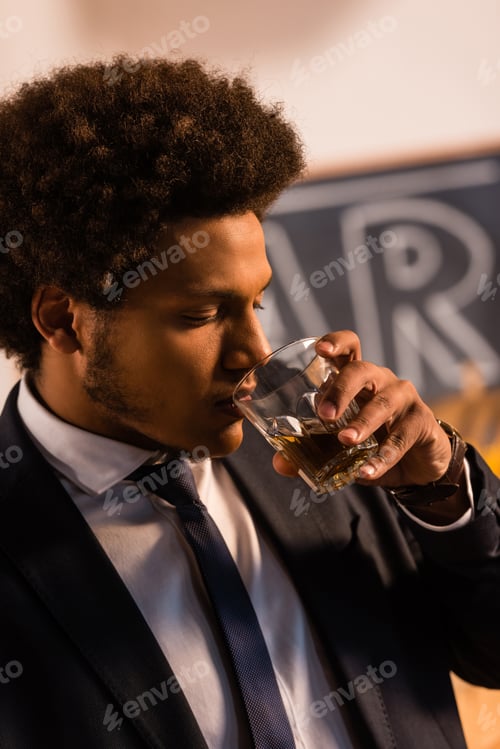 Preview: close-up view of young african american businessman drinking whisky