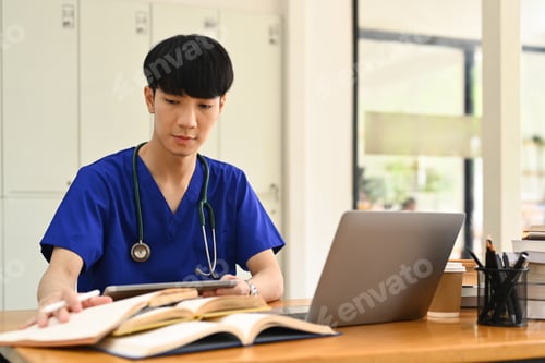 Preview: Concentrated male medical student watching online lecture on laptop. Medical internship concept.