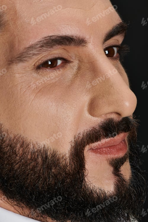 Preview: close up portrait of confident arabic man with brown eyes posing and looking away on black backdrop